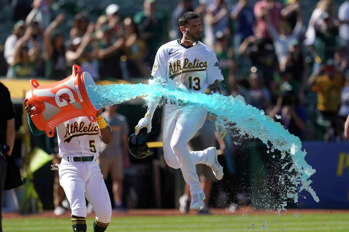 Oakland Athletics' Luis Barrera (13) jumps through Gatorade thrown by Tony Kemp (5) after hitting a three-run home run against the Los Angeles Angels during the ninth inning of the first baseball game of a doubleheader in Oakland, Calif., Saturday, May 14, 2022. (AP Photo/Jeff Chiu)