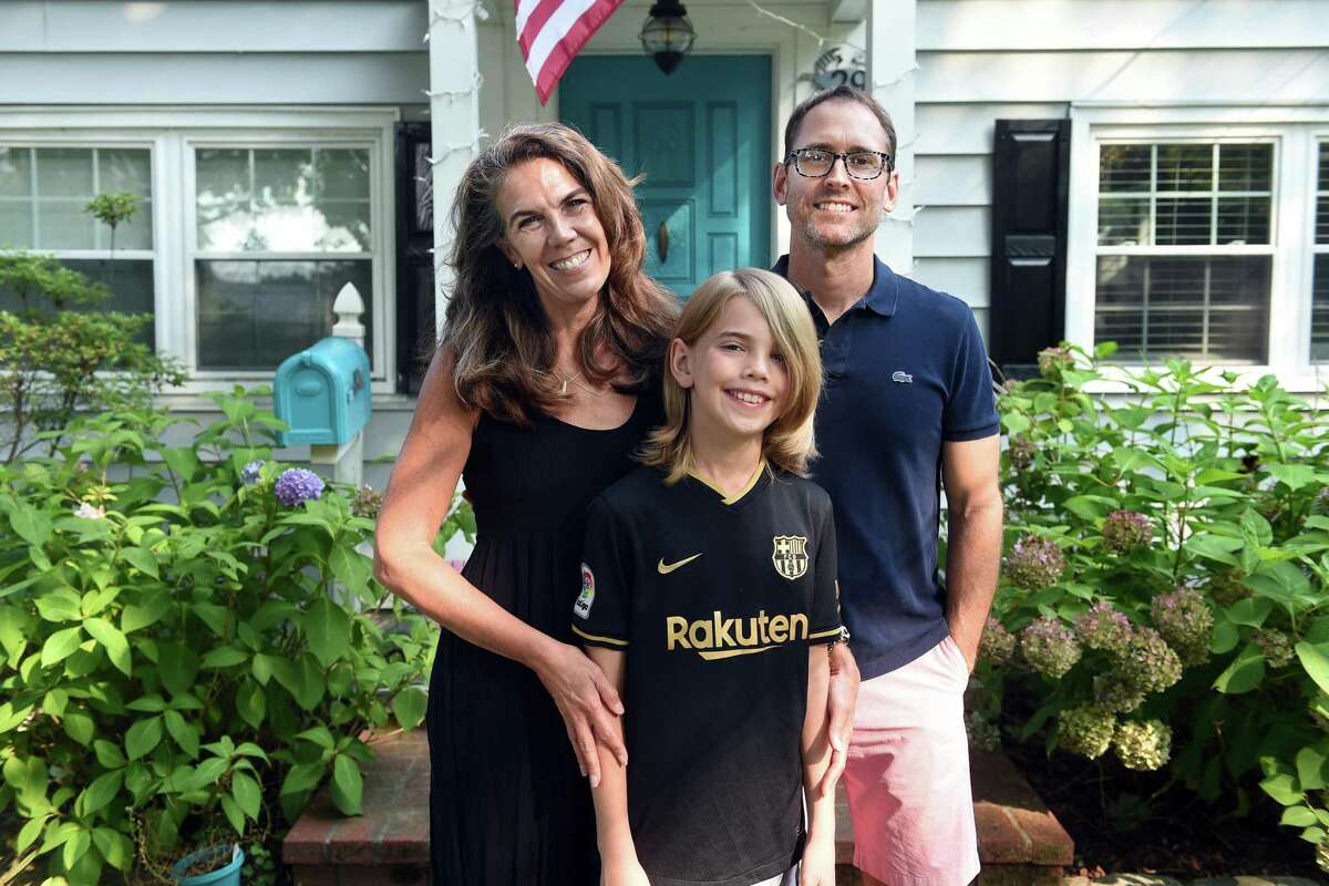 From left, Marney White, her son, Lane Mayville, and husband, Erik Mayville, photographed in front of their home on July 27, 2021.