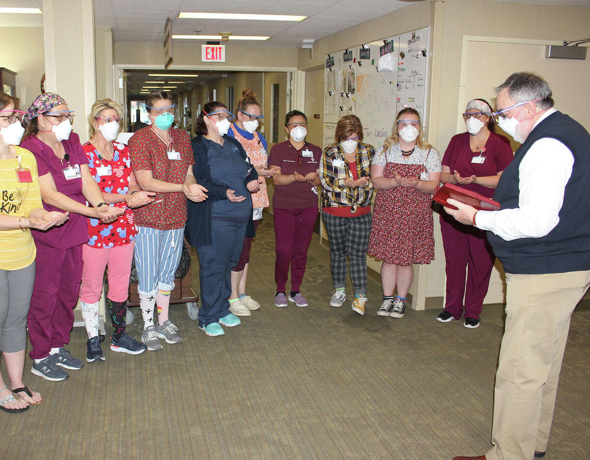 Pastor Daniel Hofmann, of Reed City, United Methodist Church, gives a blessing to members of the nursing team at Spectrum Health Reed City Hospital Rehabilitation and Nursing Center. 