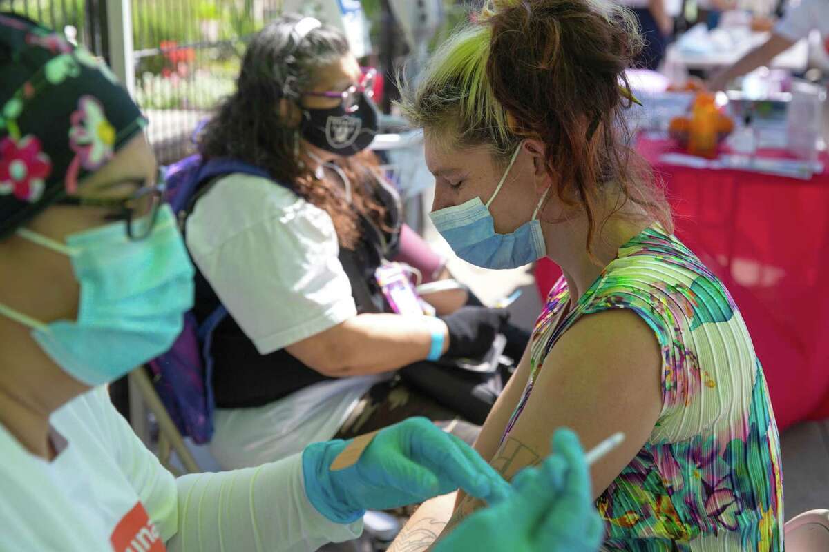 Meriem Nour, registered nurse from Mission Neighborhood Health Center, administers a COVID vaccination to Stephanie Lynn Garcia during a wellness fair at In Chan Kaajal Park in San Francisco last month.