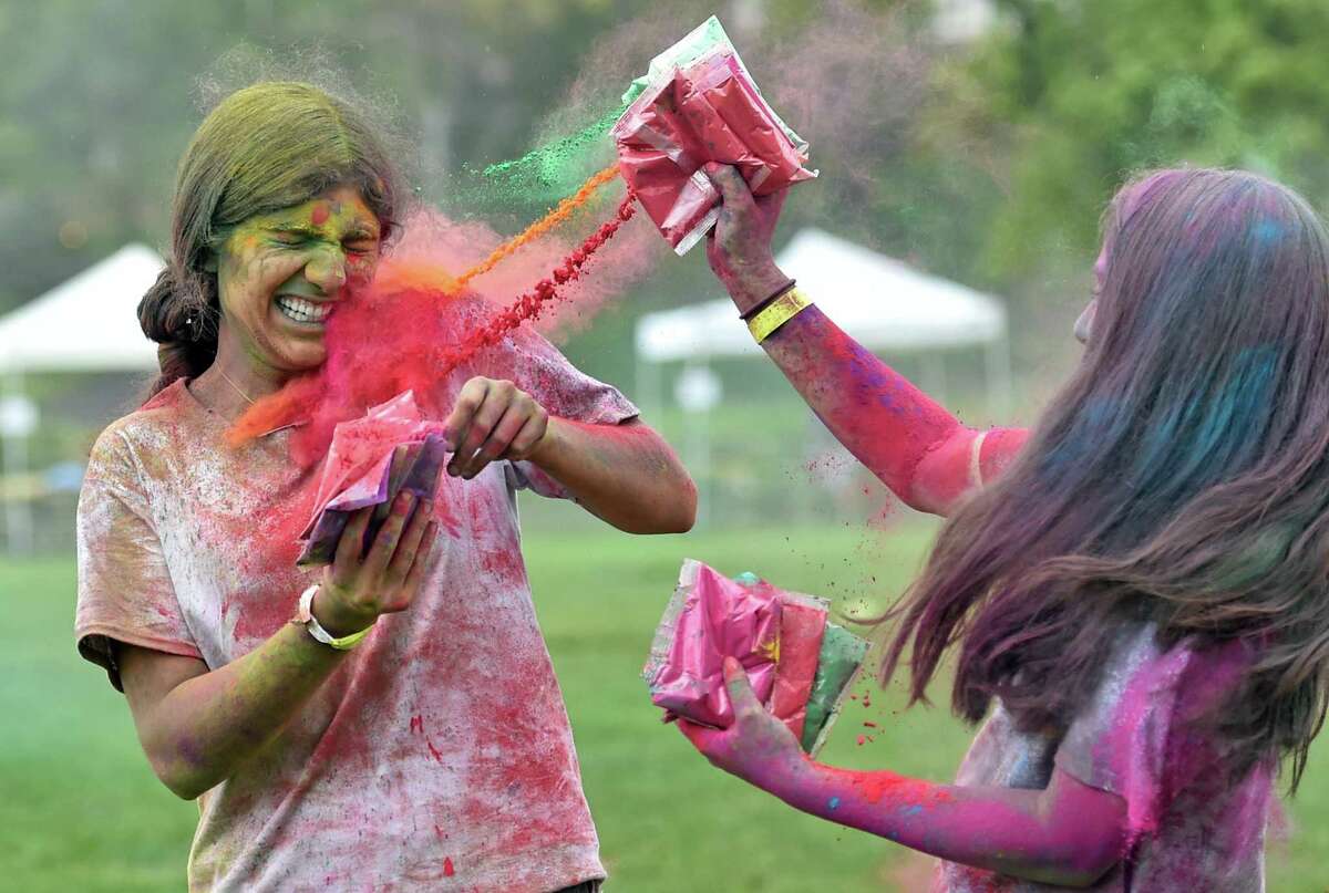 Mali Gilbert, right, tosses colored chalk dust onto her friend Sejal Virk on Saturday during the India Cultural Center of Greenwich’s Holifest and Color Throw at Roger Sherman Baldwin Park. The Color Throw was highlighted, but the event also featured Indian food, henna tattoos and other arts and crafts, and music by DJ Kunjun.
