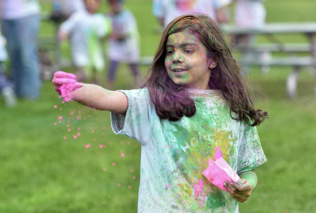 As she spins around, Elise Banchal, 8, releases colored chalk dust during the India Cultural Center of Greenwich's Holifest and Color Throw at Roger Sherman Baldwin Park in Greenwich, Conn., on Saturday May 14, 2022. Although the Color Throw is highlight of event, there were plenty of other activities like Indian food, arts and crafts, DJ Kunjun providing music, henna tattoos and an ice cream truck.