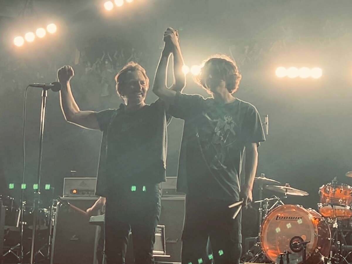Pearl Jam vocalist and guitarist Eddie Vedder raises the hand of Bay Area high school student Kai Neukermans, 18, after he drummed with the band at the Oakland Arena on Friday, May 13, 2022.