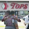 BUFFALO, NEW YORK - MAY 15: People gathered outside of Tops market embrace on May 15, 2022 in Buffalo, New York. Yesterday a gunman opened fire at the store, killing ten people and wounding another three. Suspect Payton Gendron was taken into custody and charged with first degree murder. U.S. Attorney Merrick Garland released a statement, saying the US Department of Justice is investigating the shooting "as a hate crime and an act of racially-motivated violent extremism". (Photo by Scott Olson/Getty Images) *** BESTPIX ***