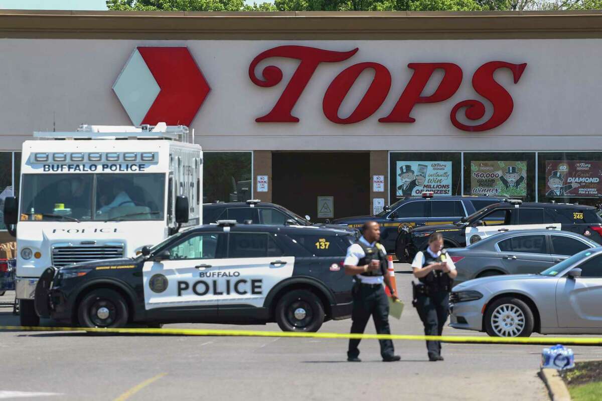 Police walk outside the Tops grocery store on Sunday, May 15, 2022, in Buffalo, N.Y. A white 18-year-old wearing military gear and livestreaming with a helmet camera opened fire with a rifle at the supermarket, killing and wounding people in what authorities described as “racially motivated violent extremism.”