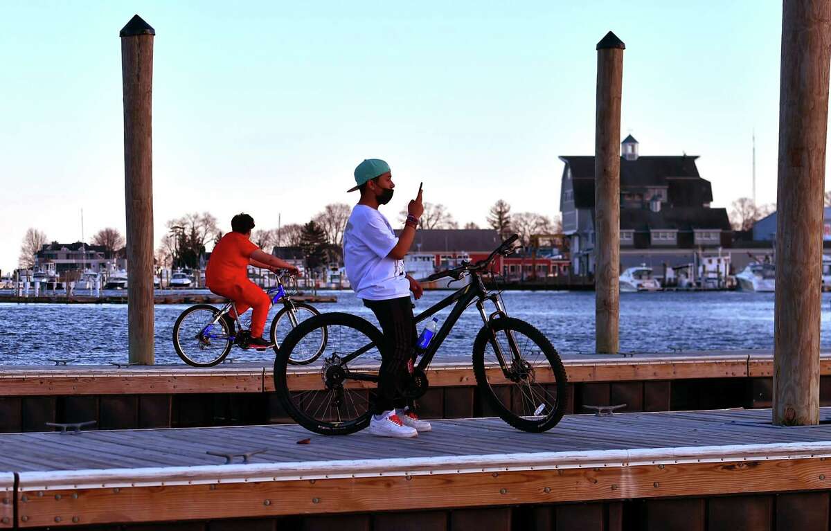 Jonathan Morales hangs out on the public docks with another friend, in back, and another not pictured, while riding their bikes around Veterans Park in Norwalk, Conn., on Friday April 8, 2021.