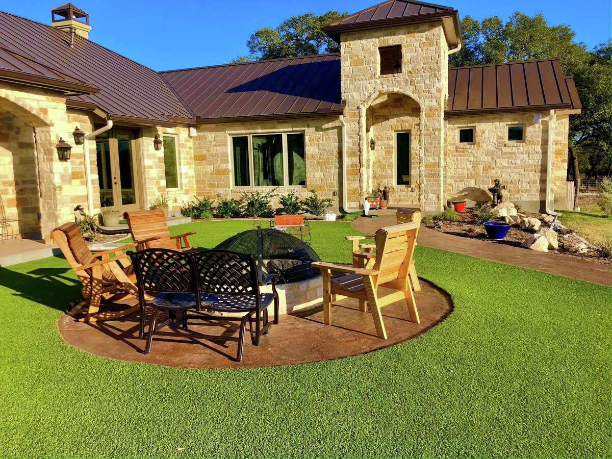 While artificial turf doesn't have to be watered, it's not maintenance-free. Leaves and pollen will still fall on it and dogs, cats and wild animals will still do their business on it. This courtyard with a fire pit is in Bulverde.