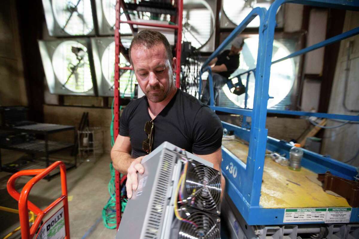 Caleb Ward, left, president and CEO at Geosyn Mining, and his partner Jeremy McNutt, prepare to install more crypto miners at their warehouse location northwest of Fort Worth, on Saturday, March 14, 2022. Founded by Caleb Ward and Jeremy McNutt, two oil and gas industry veterans, Geosyn Mining began operations in January 2022. These Texas entrepreneurs envision their company leveraging the power of Bitcoin to help proliferate solar energy production. (Joyce Marshall/for the Chronicle)