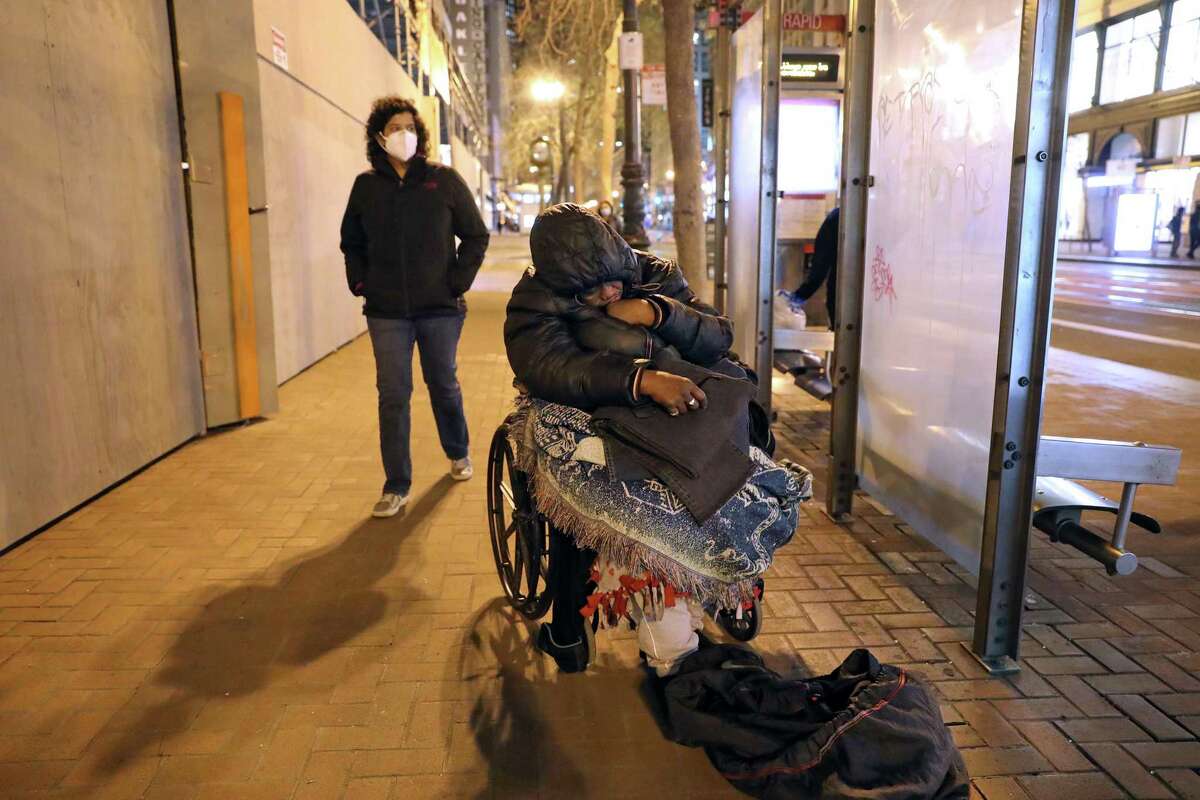 Homeless woman Demetria Block waits for a bus as Shireen McSpadden, Executive Director of the Department of Homelessness and Supportive Housing for the City and County of San Francisco, takes part in the Point In Time one-night homeless count in San Francisco, Calif., on Wednesday, February 23, 2022.
