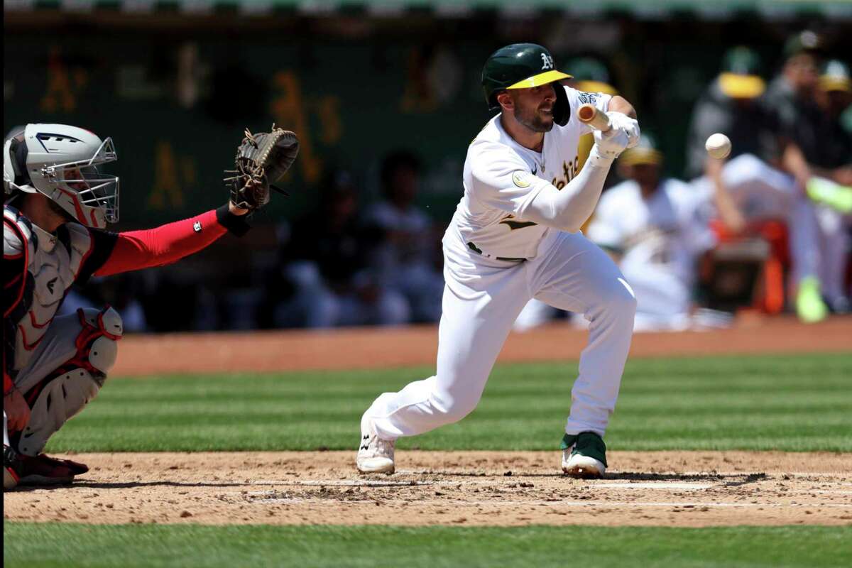 Oakland Athletics' Kevin Smith, right, hits a sacrifice bunt in front of Cleveland Guardians catcher Austin Hedges, left, during the second inning of a baseball game in Oakland, Calif., Saturday, April 30, 2022. (AP Photo/Jed Jacobsohn)