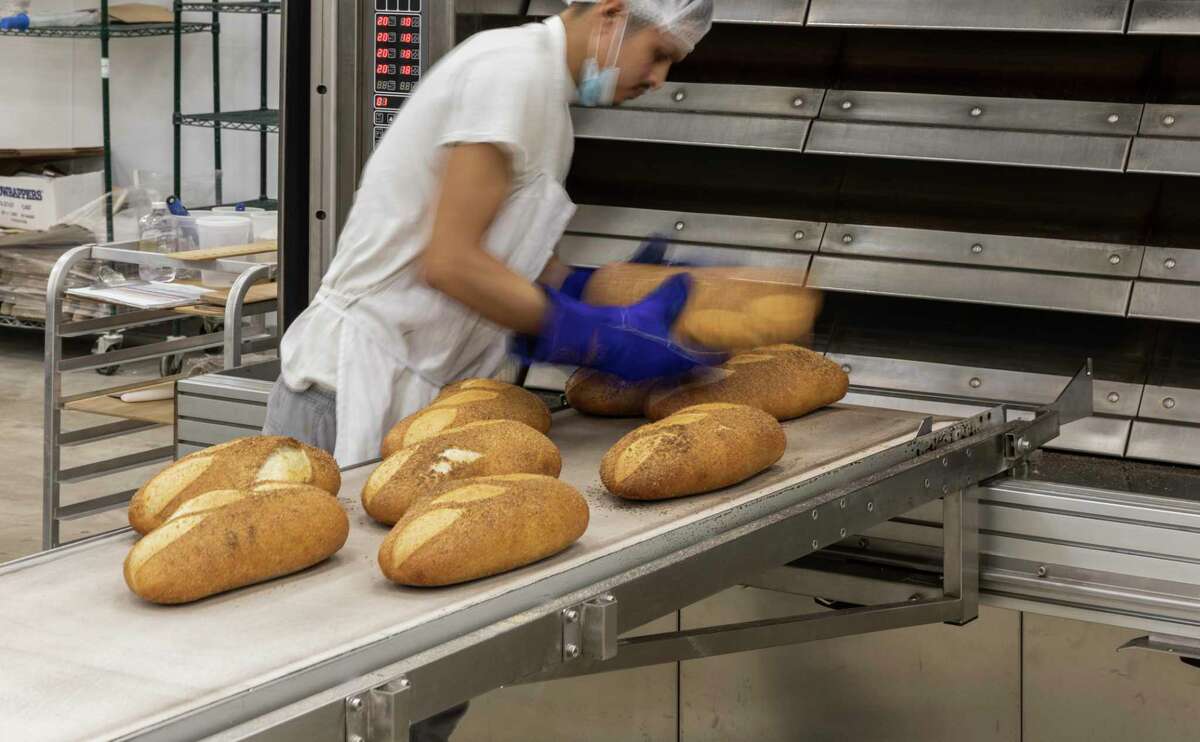 A worker pulls off fresh loaves destined for Postino wine bar restaurants in Houston at Bread Man Baking Co.