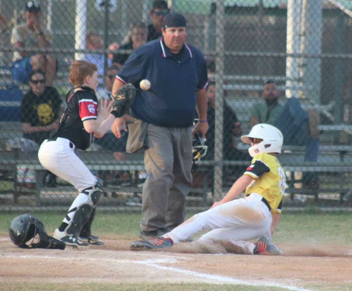 As the ball squirts away from the catcher, Pirates player Ryan Hughes slides home with one of the team's runs during their big fourth frame Monday night.