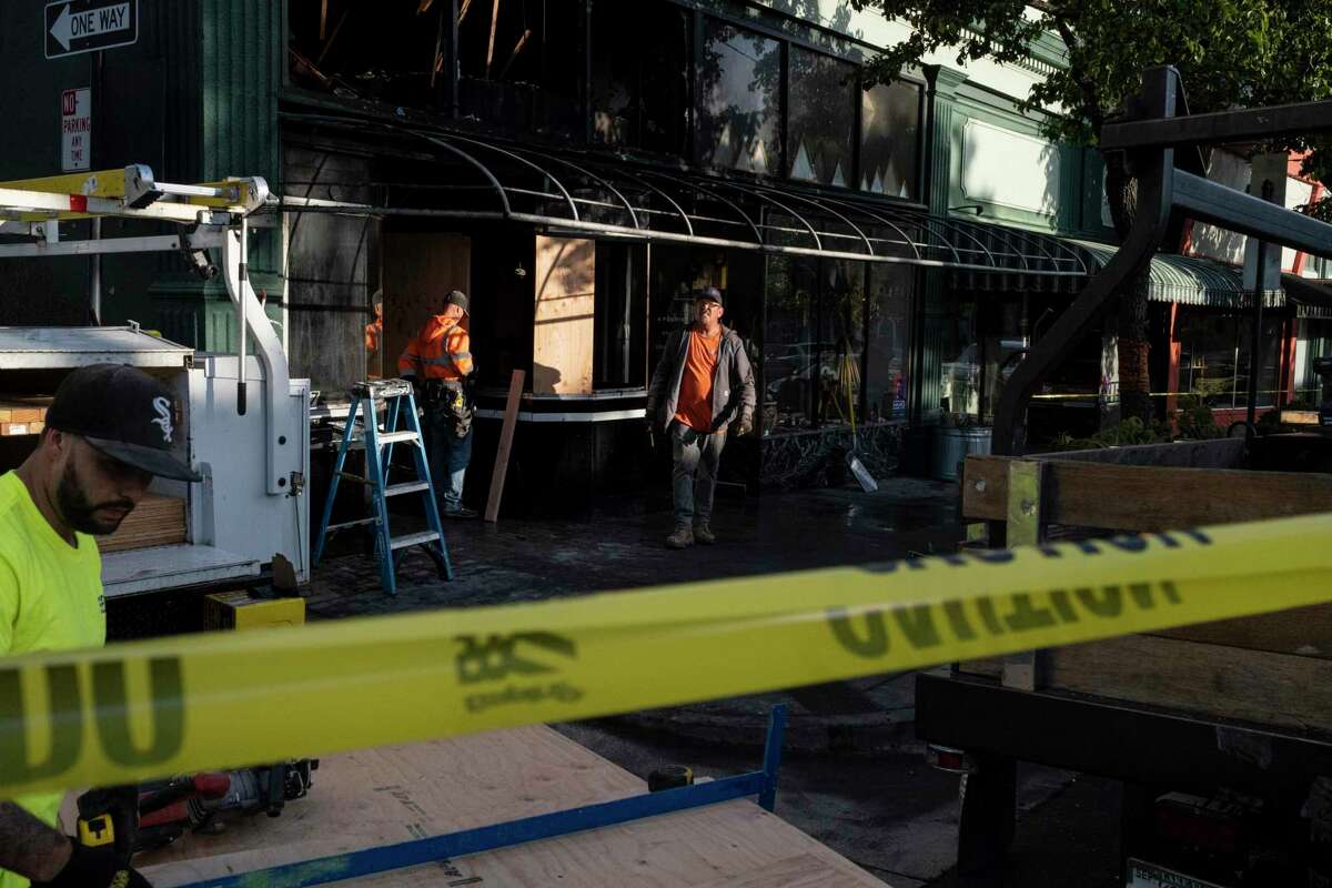 A crew secures a building on Marin Street in Vallejo, where Anchor Pantry, a small local business, was damaged in a fire.