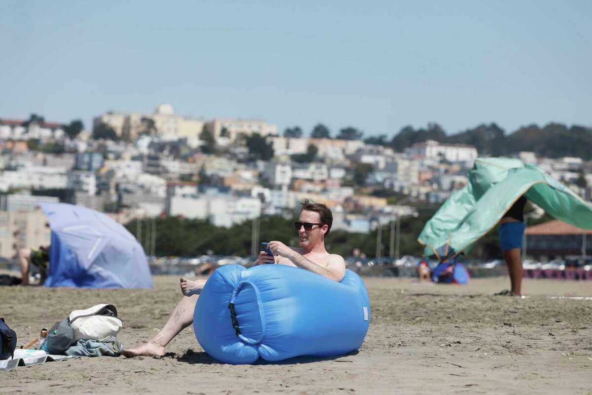 David Giannino of San Francisco enjoys the sun as he sits on an inflatable seat last month at Ocean Beach in San Francisco.