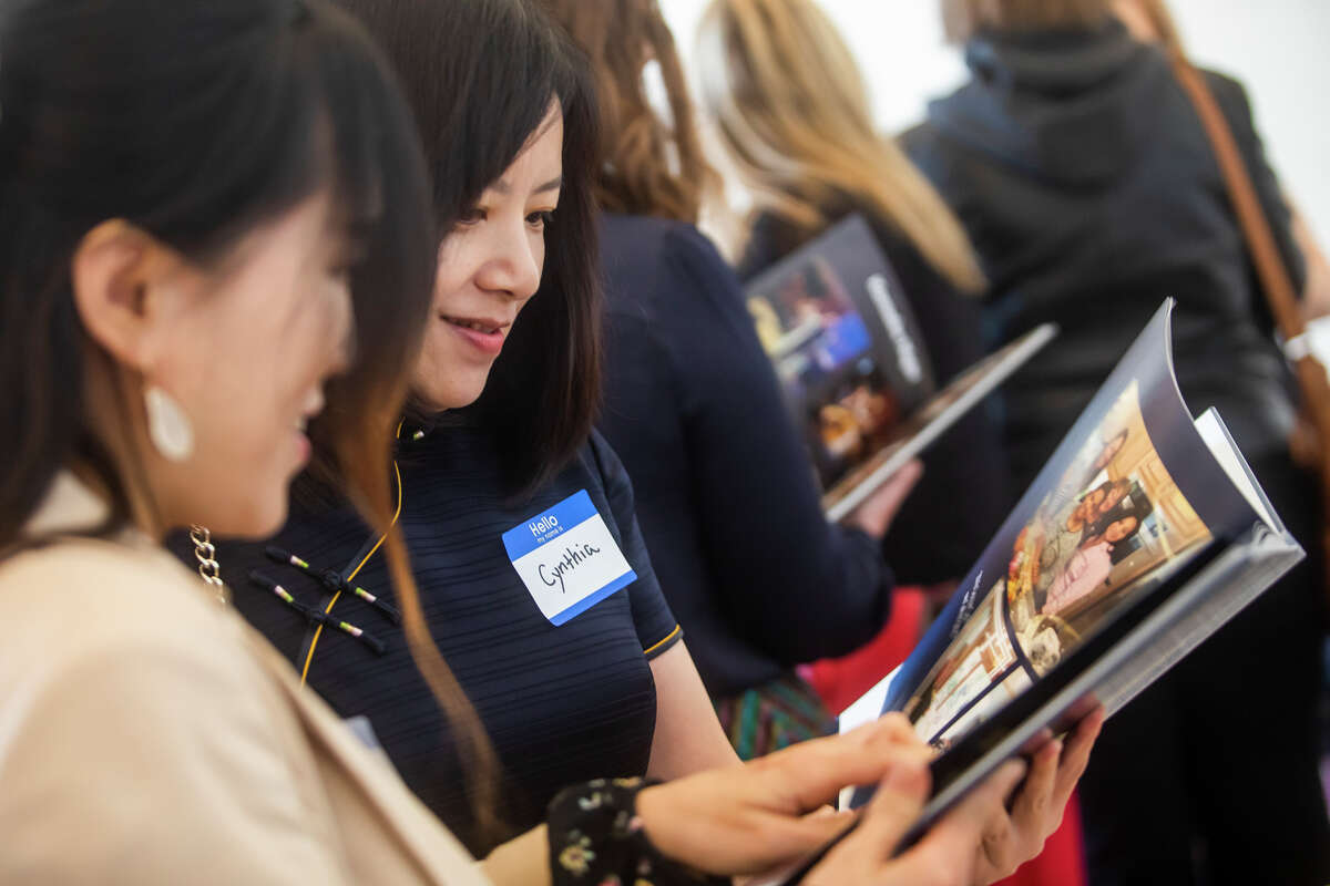 Cynthia Chen, right, and Grace Shin, left, flip through a photo album as the International Women's Club of Midland gathers in celebration of their 50th anniversary Tuesday, May 17, 2022 at Midland Country Club.