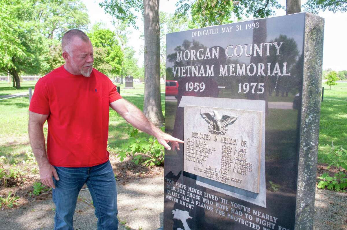 Army veteran Trevor Lahey stands next to the Vietnam War Memorial in Nichols Park while pointing out the names of some of the Morgan County men who lost their lives while serving in Vietnam.