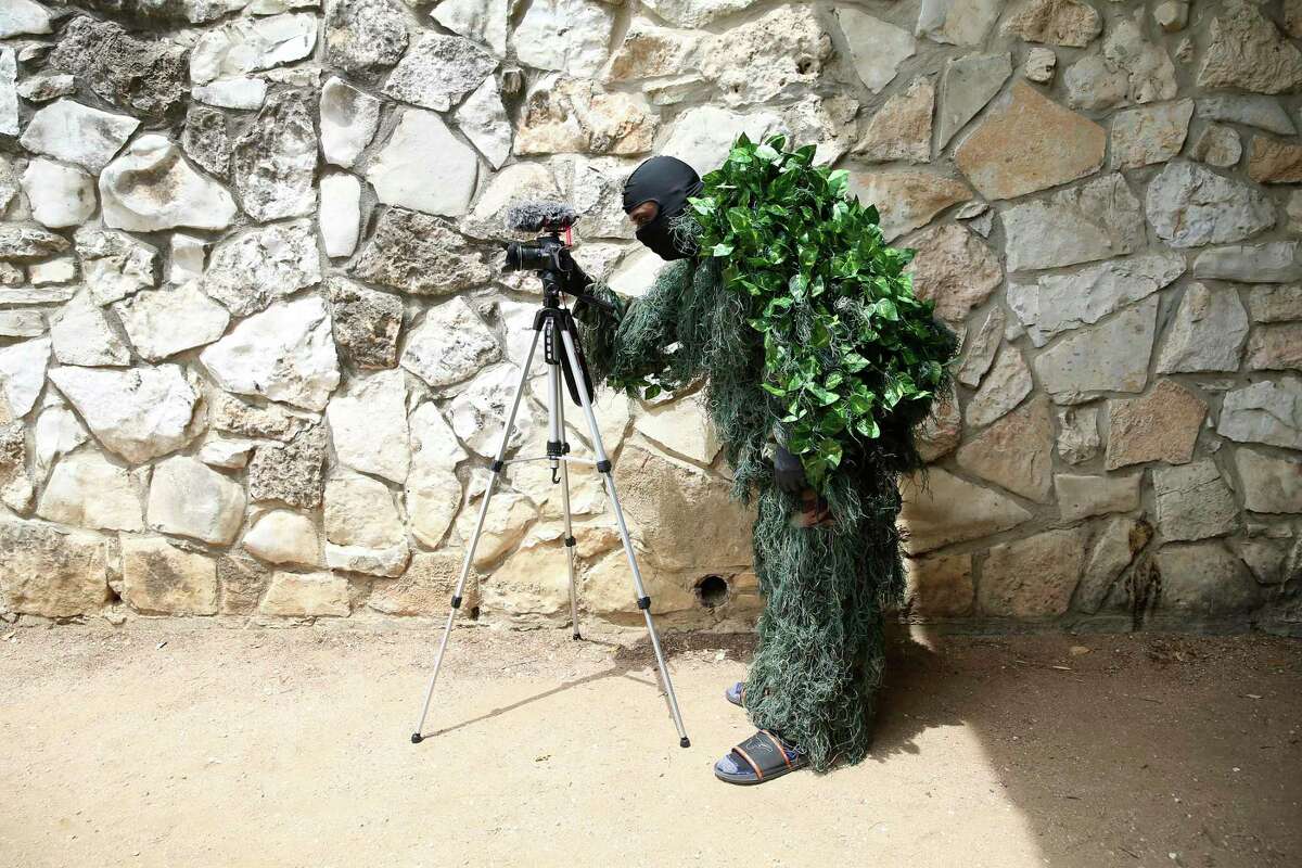 Joe Jones, 33, sets up a camera as he prepares to prank people along the River Walk. Known as the Texas Bushman, Jones covers himself in fake ivy and squats in a planter to scare passersby. Jones records the interactions and posts the videos on YouTube and social media.