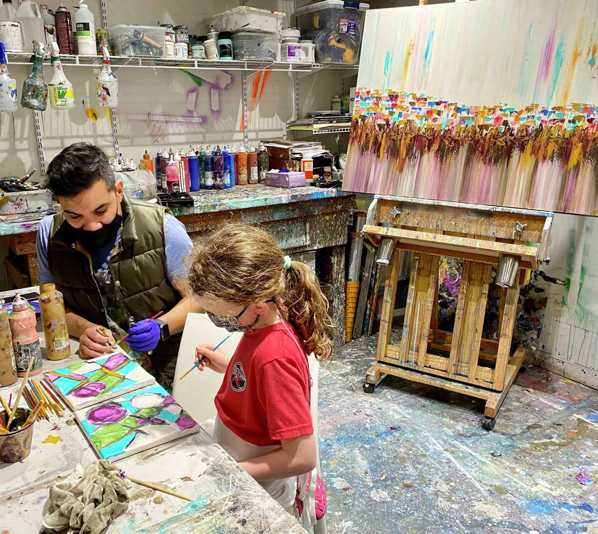 Nora Verville, 9, from The Woodlands, is a resident artist at The Bella Bottega artist community just off FM 1488 at Honea Egypt Road. As of this March, she’s also an artist in residence at Gallery Skye in Houston. Her work has been displayed at several galleries with many pieces selling. Pictured here, Nora paints with Houston artist Edgar Medina.