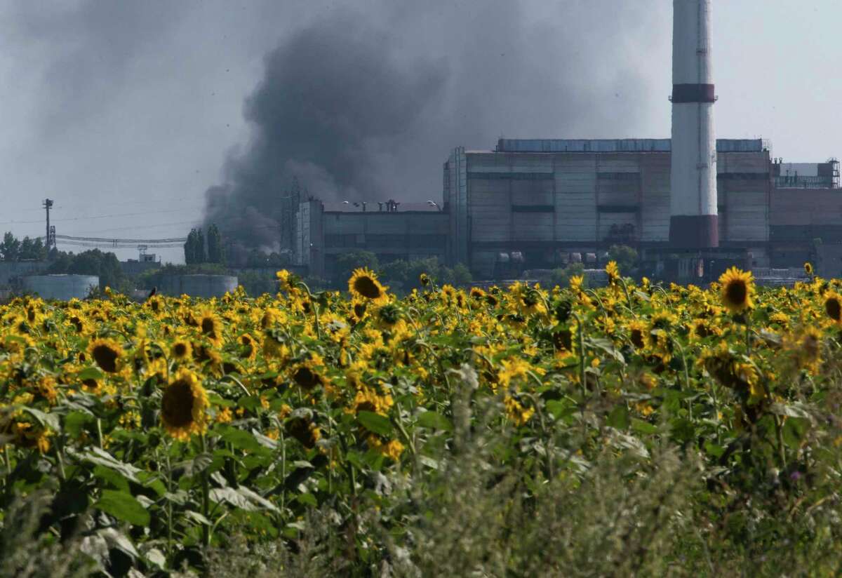 Smoke from an oil refinery rises over a field of sunflowers near the city of Lisichansk, Luhansk region, eastern Ukraine, in 2014. Global cooking oil prices have been rising since the COVID-19 pandemic began and Russia’s war in Ukraine has sent costs spiraling. It is the latest fallout to the global food supply from the war, with Ukraine and Russia the world’s top exporters of sunflower oil. And it’s another rising cost pinching households and businesses as inflation soars.