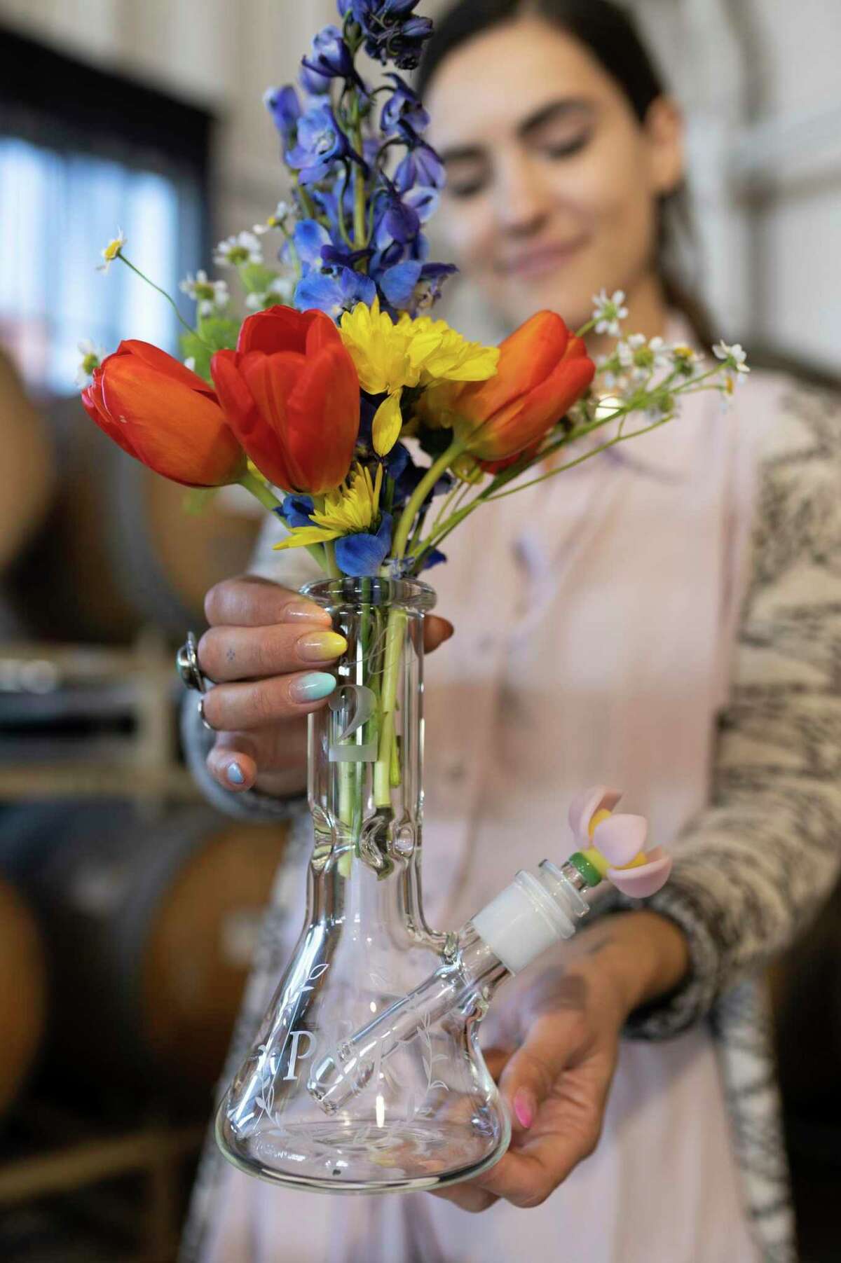 Whitney Adrian, of Empire Glassworks, shows one of the company’s custom etched water pipes, which doubles as a centerpiece that can be used at weddings or other events.