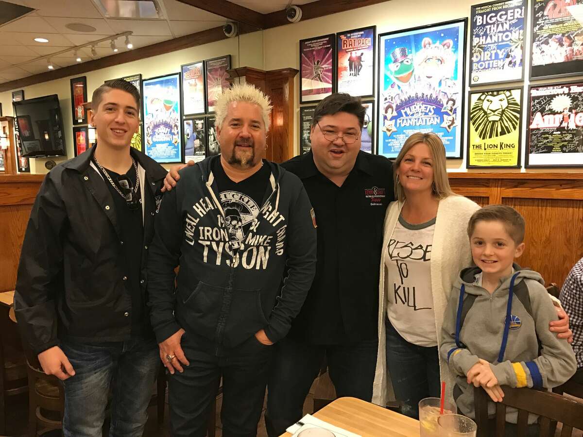 Guy Fieri and his family talking in a Schmoz room.