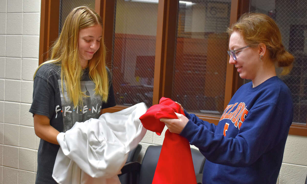 Jacksonville High School seniors Elizabeth Solterman (left) and Madison Fanning prepare robes for graduation.