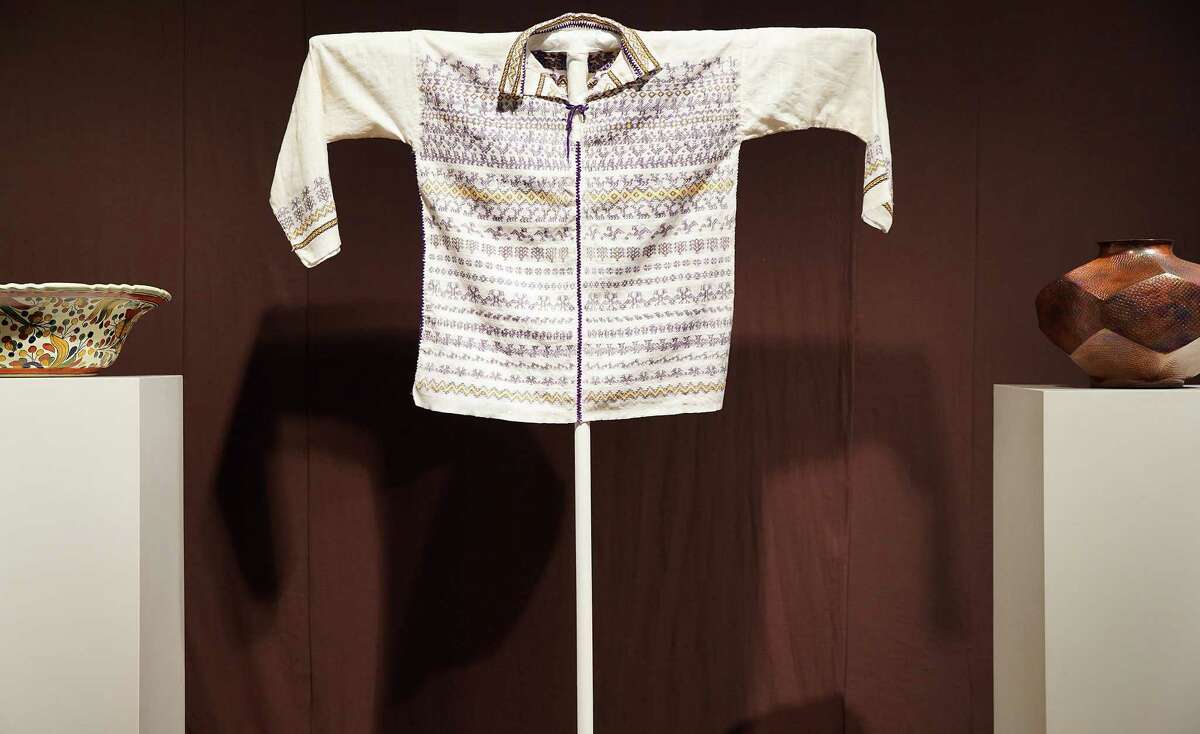 A man’s shirt with woven design is centered between two vessels at the John Fairey Garden Gallery on Tuesday, May 17, 2022 in Hempstead. The art work for the exhibit titled “Back to the Garden” is from The John Gaston Fairey Mexican Folk Art Collection at the Art Museum of Southeast Texas.