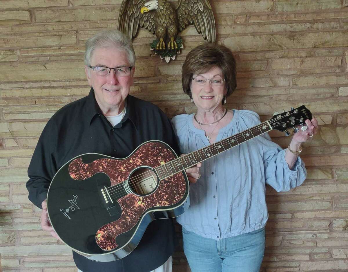 Conroe concert promoters Gene and Betty Wolf are helping longtime musician Bobby Flores in his fight against Stage IV Esophageal Cancer. They have secured a guitar signed by George Strait and a violin signed by Ray Price to auction off for Flores benefit. Gene and Betty Wolf are pictured with the signed guitar.