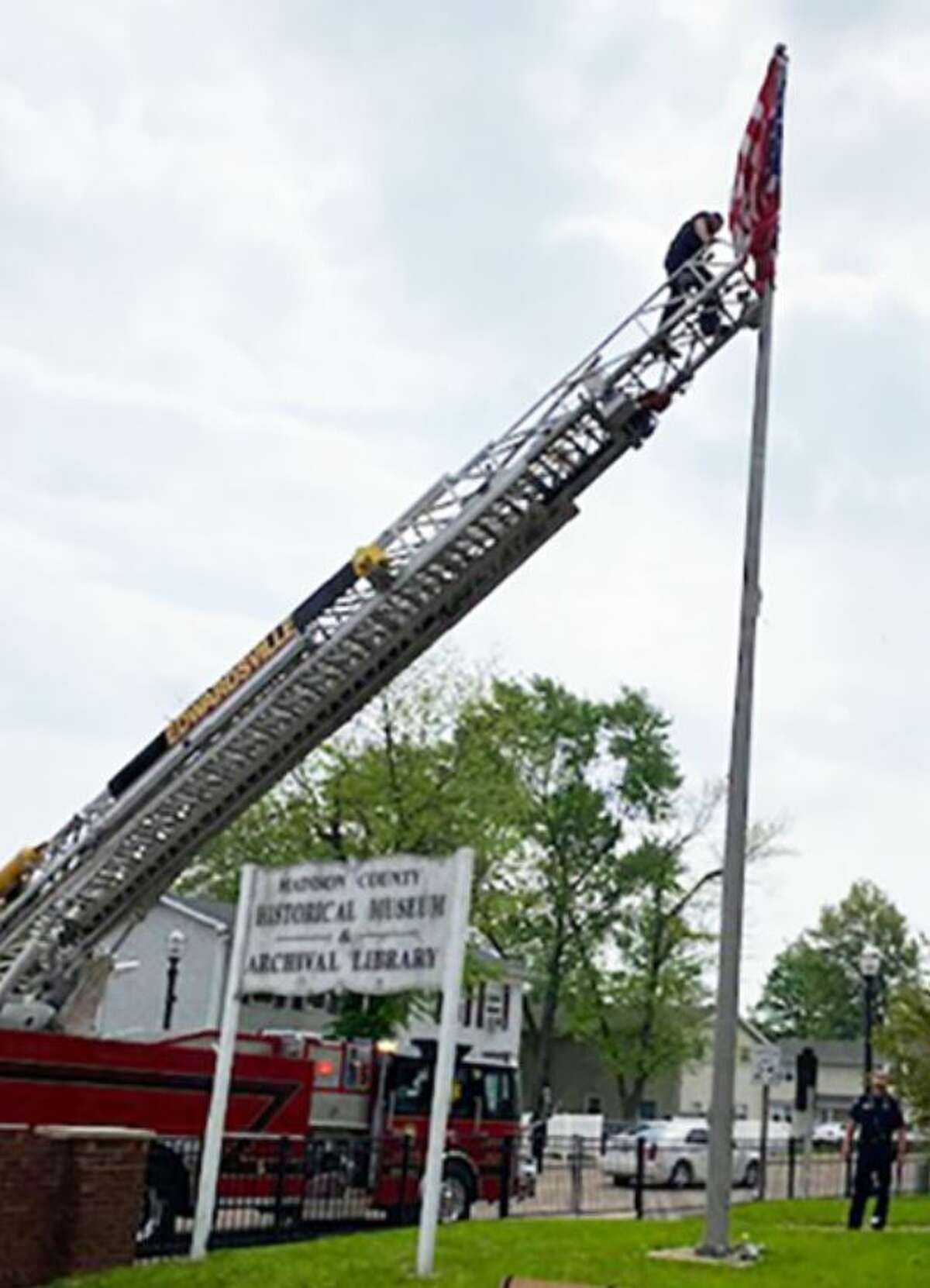 The Edwardsville Fire Department uses a ladder truck to remove a tattered American flag that had been caught on a chain on a flagpole at the Madison County Historical Society Museum and Archival Library in Edwardsville.
