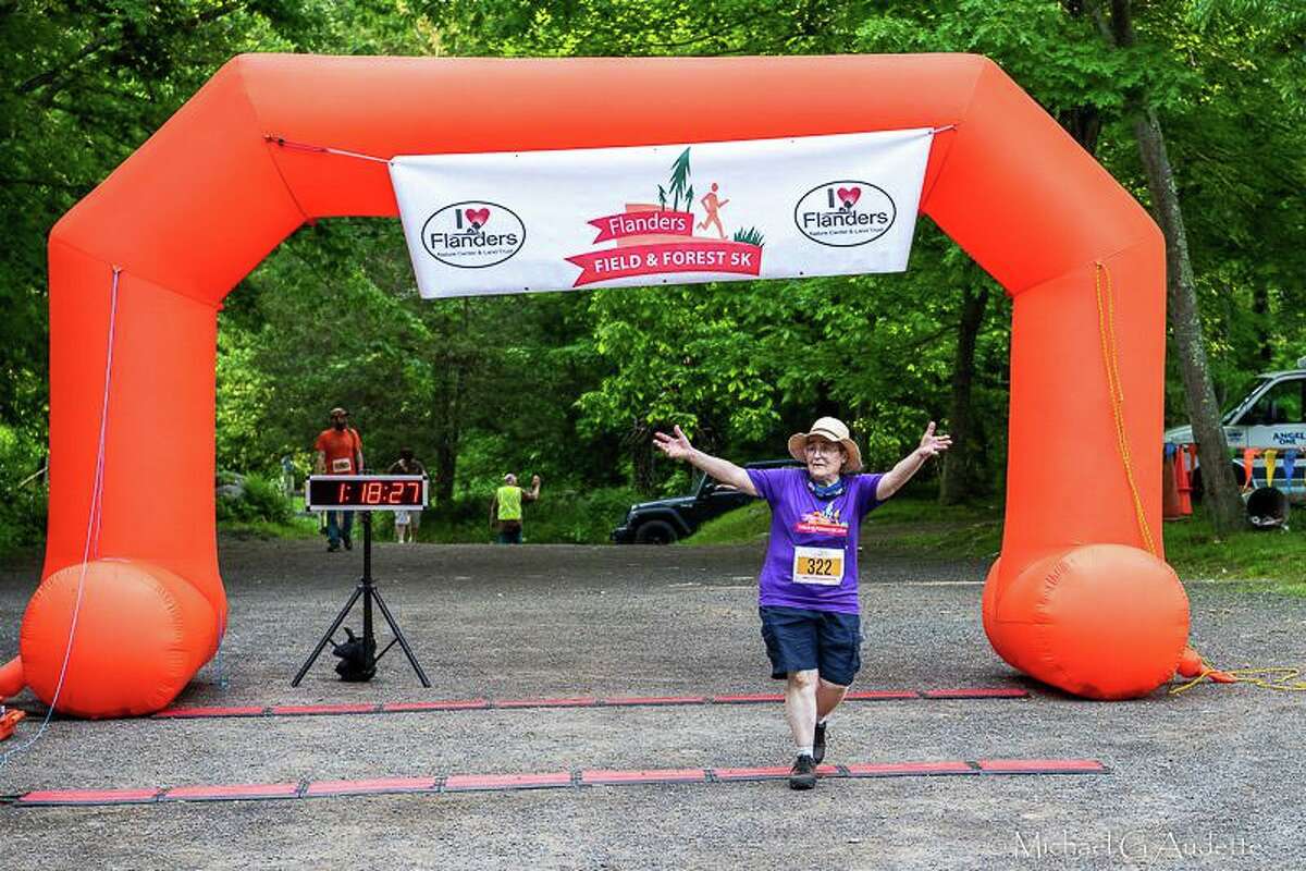 Flanders Nature Center & Land Trust is preparing for its 7th Field & Forest 5K Trail Run, set for June 3. Roberta Moran crosses the finish line at 2021 5K. Pictured are Race Chairs Heidi Ball and Heather Dever