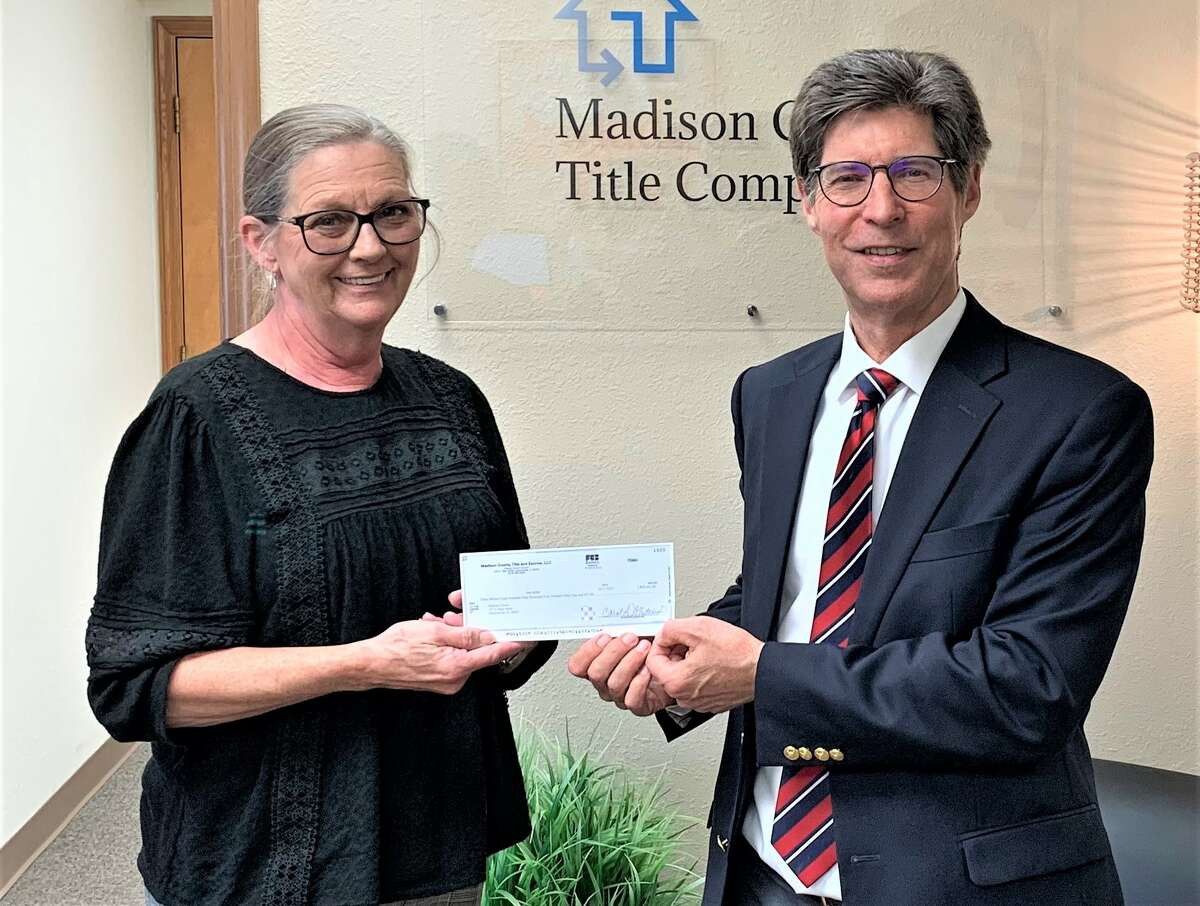 Madison County Escrow Closer Carol Whiteside passing Chairman Kurt Prenzler a check for $3.8 million for the sale of the Plum Street property. The Staenberg Group, which is developing the nearby Orchard Town Center in Glen Carbon, was the sole bidder for the property.