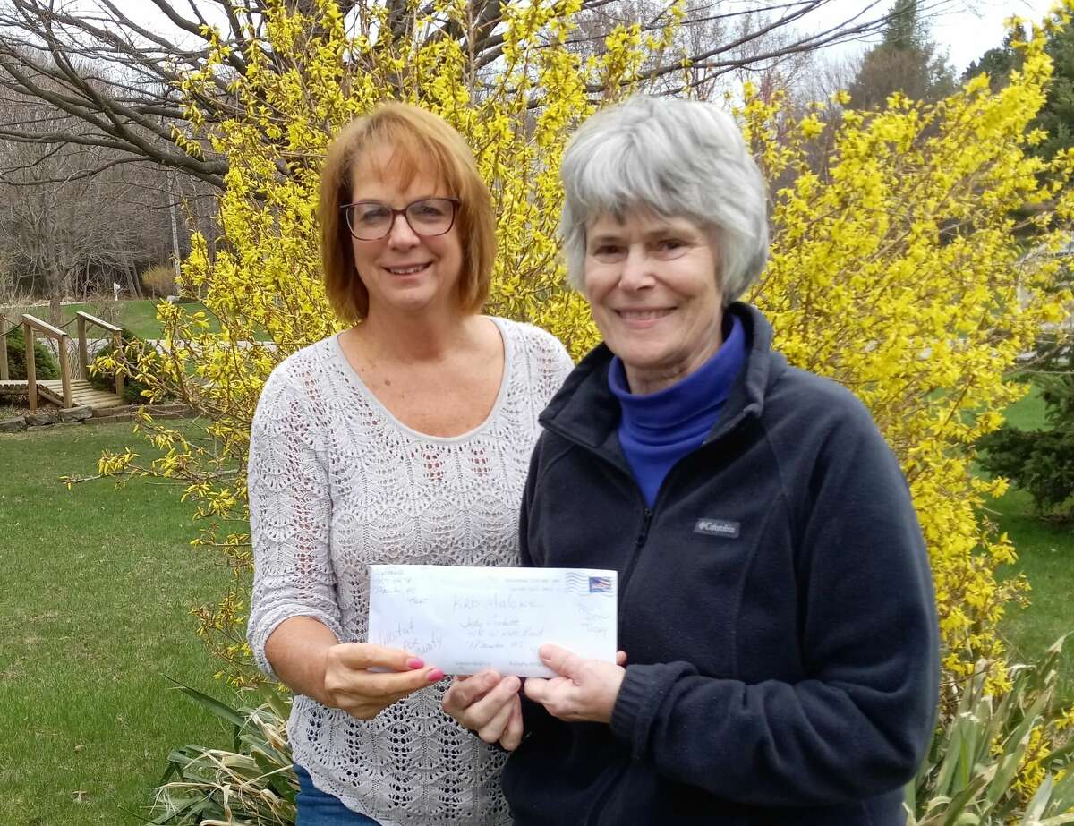 Judy Crockett presents Habitat for Humanity of Manistee County board member Kris Malone with $9,900 raised by 100 Women Who Care Manistee County in April 2022.