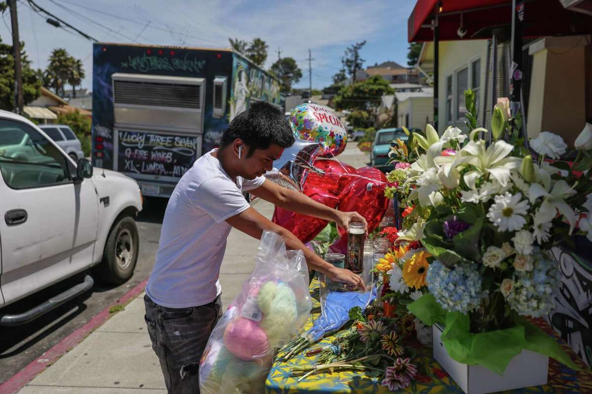 Ben Domingo places a candle Thursday at a memorial outside Lucky Three Seven in Oakland for the restaurant’s co-owner, Artgel “Jun” Anabo, who was fatally shot the night before.