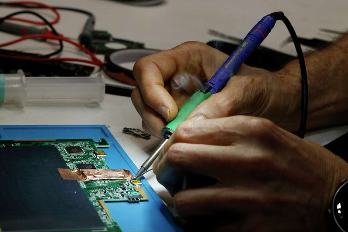 Le technicien Del Jaljaa utilise un outil de soudure sur un circuit imprimé à San Francisco Computer Repair.