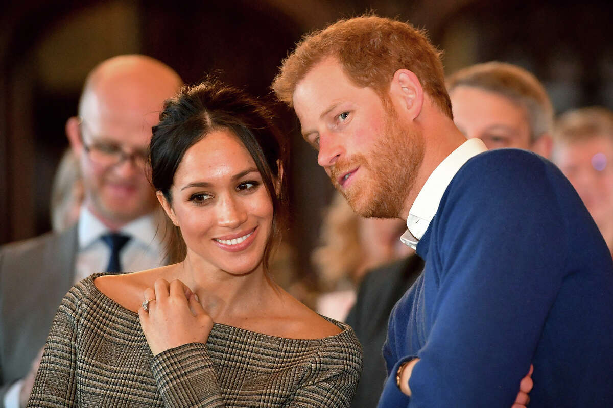 Prince Harry whispers to Meghan Markle as they watch a dance performance by Jukebox Collective in the banqueting hall during a visit to Cardiff Castle on January 18, 2018 in Cardiff, Wales, The couple keep their primary home and are raising their two children in Montecito, a place that is both home to the world's wealthiest and most famous and rife with danger from climate change. 