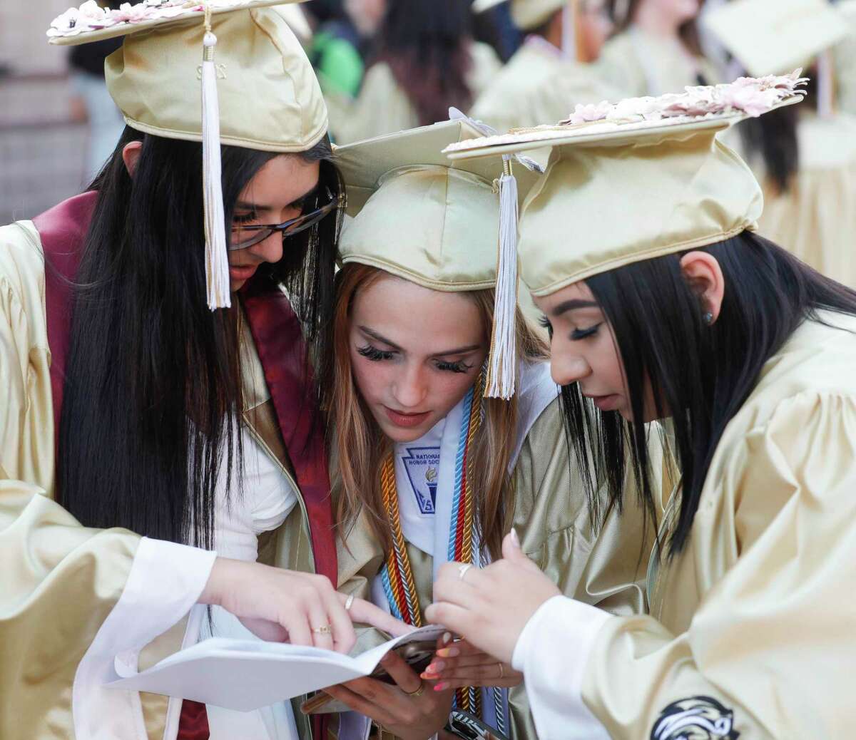 Natalia Rodriguez, Luisa Aloise and Brissa Elvira check the program before a graduation ceremony for Conroe High School at Cynthia Woods Mitchell Pavilion, Thursday, May 19, 2022, in The Woodlands.