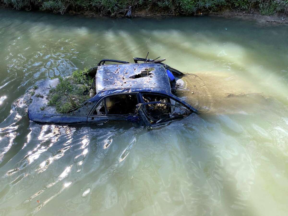 Plants grow from a partially submerged car in Hall Bayou.