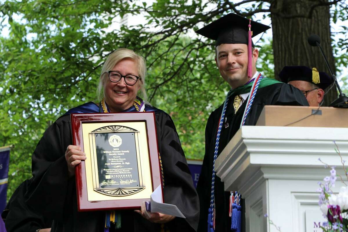 Jean Sampson, left, receives the 2022 William Norman Grandy Faculty Award from Alumni Association President Ryan Furniss during the McKendree University commencement.