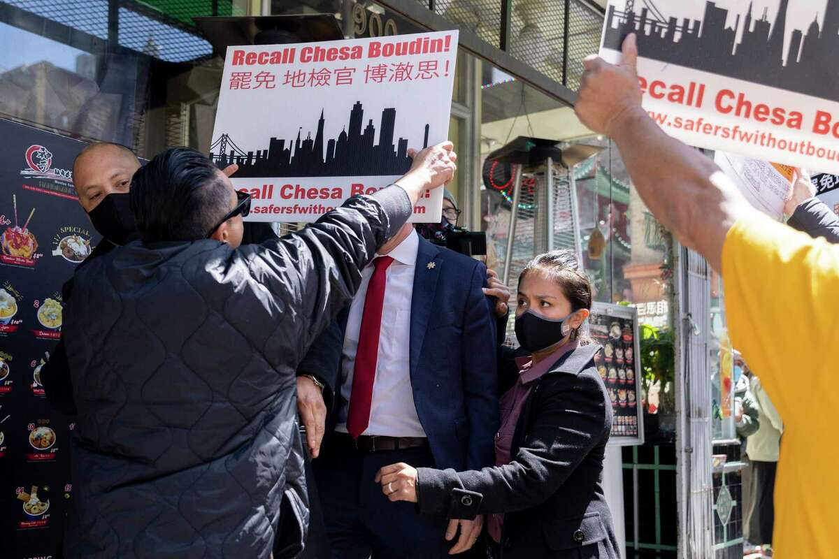 Security guards shield San Francisco District Attorney Chesa Boudin from supporters of the campaign to recall him as they stand outside of Magical Ice Cream on Grant Avenue in San Francisco on April 11.