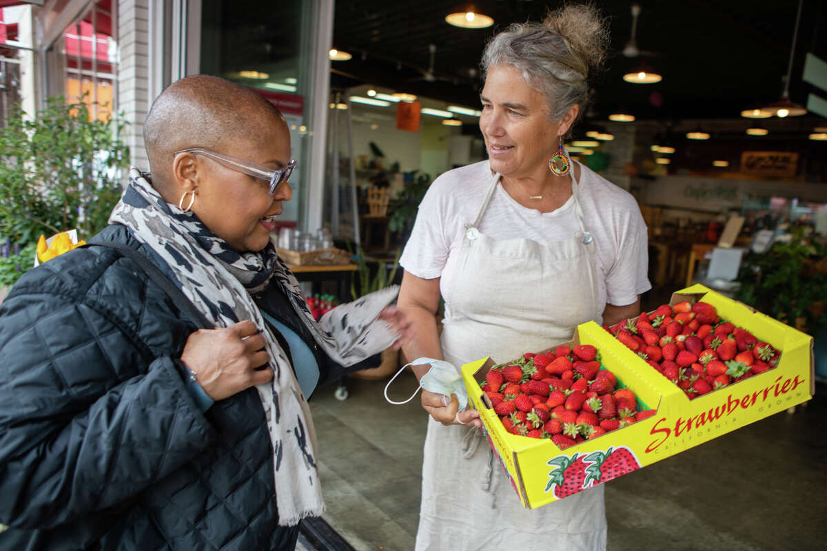 Chef Tonya Holland (left) looks at strawberries her friend Romney Steele, the owner of The Cook and Her Farmer, just bought at the Old Town Oakland Farmer's Market in Oakland, California on May 6, 2022 .