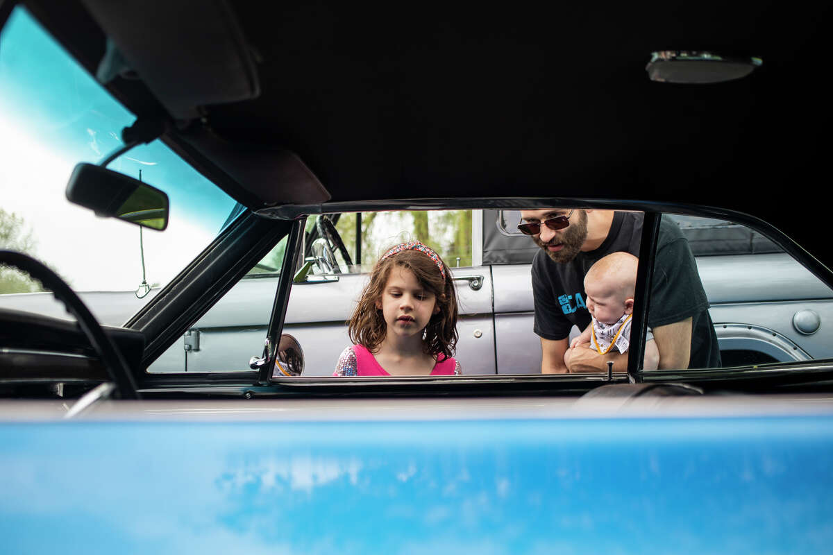 From left, Mckenzie Walther, 6, Corey Walther and Peyton Walther, 4 months, check out the interior of a 1967 Chevrolet Chevelle Super Sport during the Sanford Rising Car Show Friday, May 20, 2022 in Porte Park.