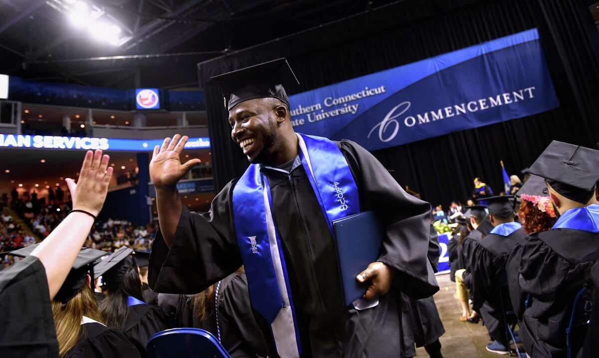 Schneither Nogaisse (center) high fives Gabrielle Rousseau (off camera) after receiving his diploma at the Southern Connecticut State University commencement at the Total Mortgage Arena in Bridgeport on May 20, 2022.