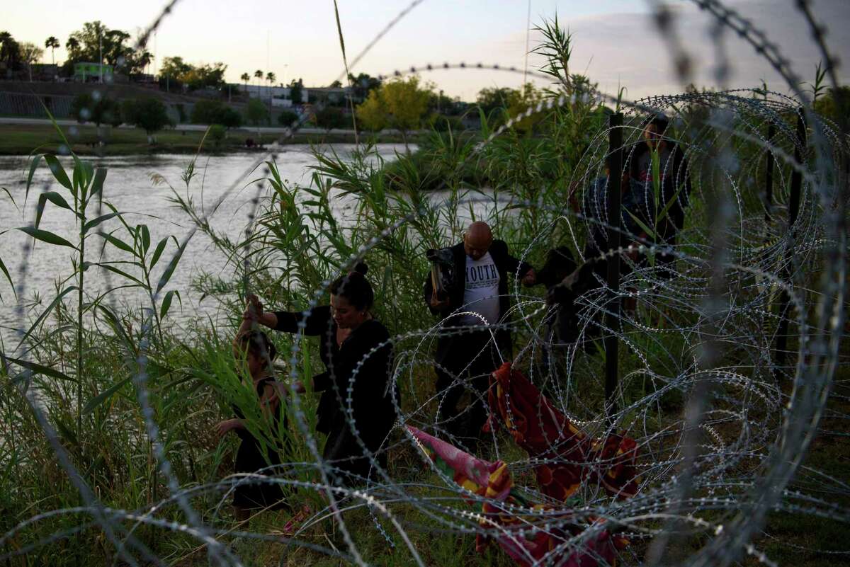 Migrants navigate barbed wire after crossing the Rio Grande at Eagle Pass, Texas, on April 26, 2022. Homeland Security officials have said they are preparing for as many as 18,000 migrants a day after Title 42 expires, while most predictions hover around 12,000.