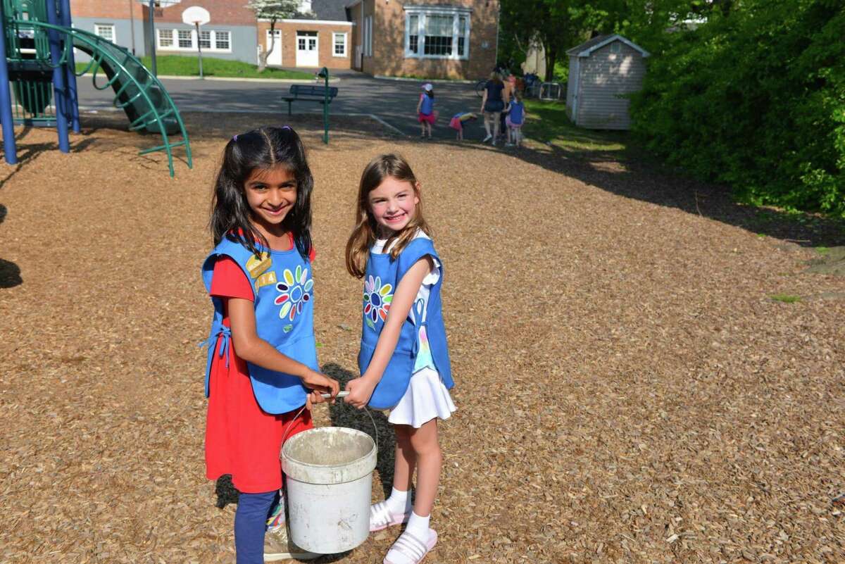 Ruby Shah and Olivia Brown, Daisy level Girl Scouts, carry compost as they work on the Secret Garden at Old Greenwich School on Sunday.