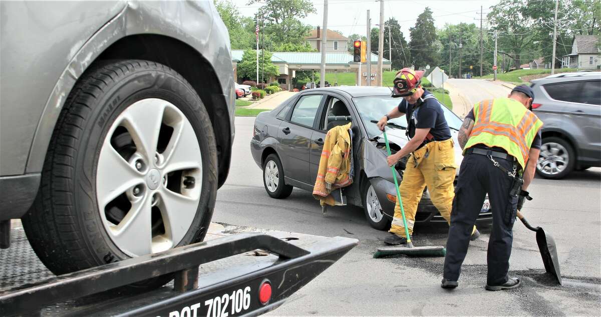 Firefighters clean up debris as one car is loaded onto a tow truck after a two-car accident at the intersection of Homer Adams Parkway and Humbert Street in Alton Friday afternoon. According to first responders on the scene, it appeared that one vehicle was making a turn and was struck by the other. One of the vehicles flipped over, but by the time firefighters arrived all the occupants were out and talking to one another. No major injuries were reported at the scene, and the overturned car was quickly righted.