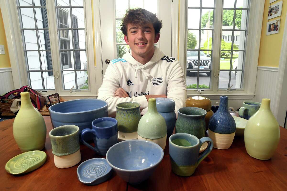Trumbull High School junior Matthew Wich poses with some of his ceramic pottery in his home in Trumbull, Conn. May 18, 2022. Wich has started a nonprofit organization, Ceramics for Soccer, to raise money to provide soccer equipment for children in developing nations.