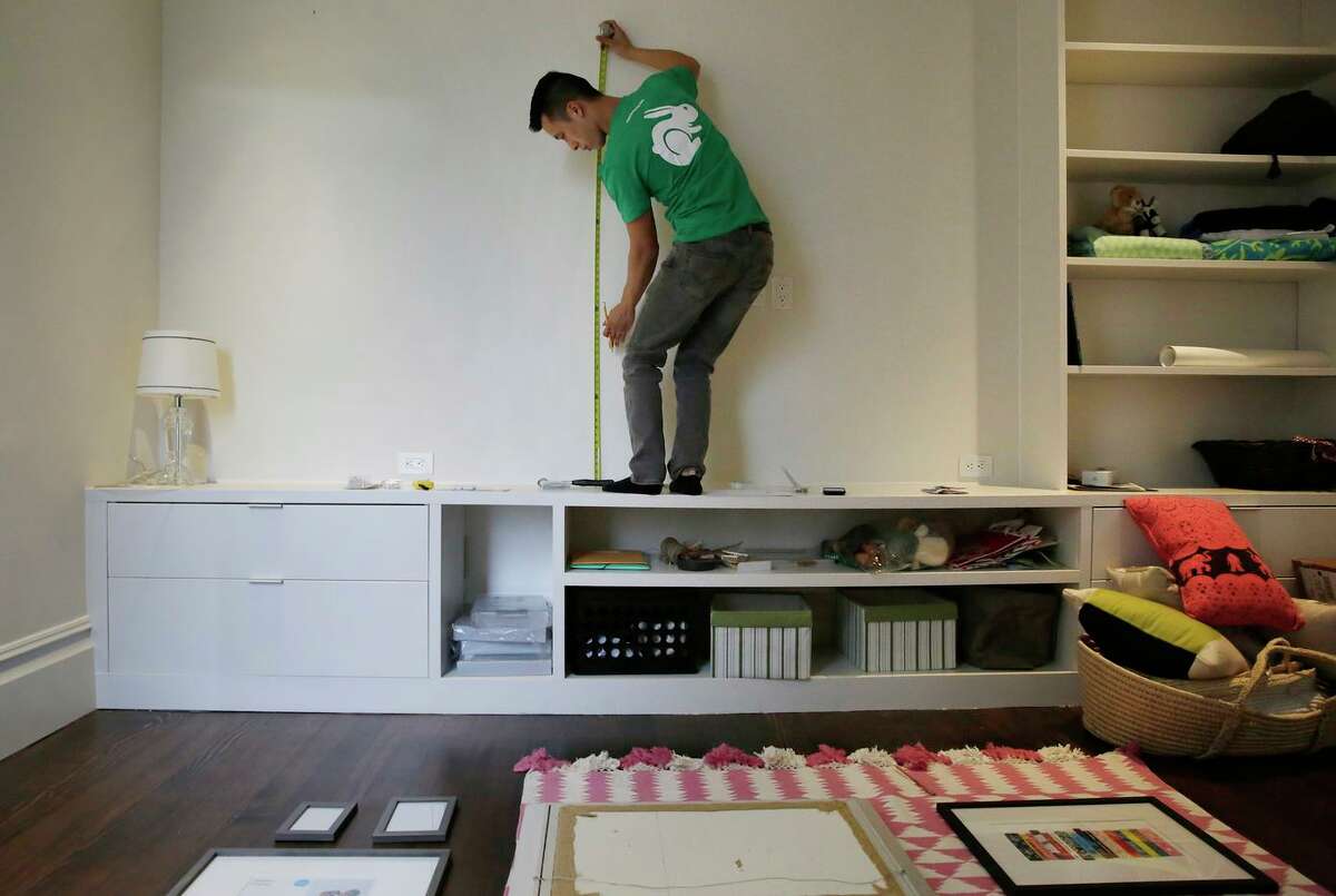 Thai-can “Paul” Nguyen, Taskrabbit tasker, takes measurements while hanging picture frames for a client in San Francisco. The company, which is headquareted in the city, has announced it will close all office spaces become a remote work operation.
