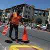 Roque C. with Cato’s Paving places cones on the street as he works in front of the Springline apartments in Menlo Park, Calif.