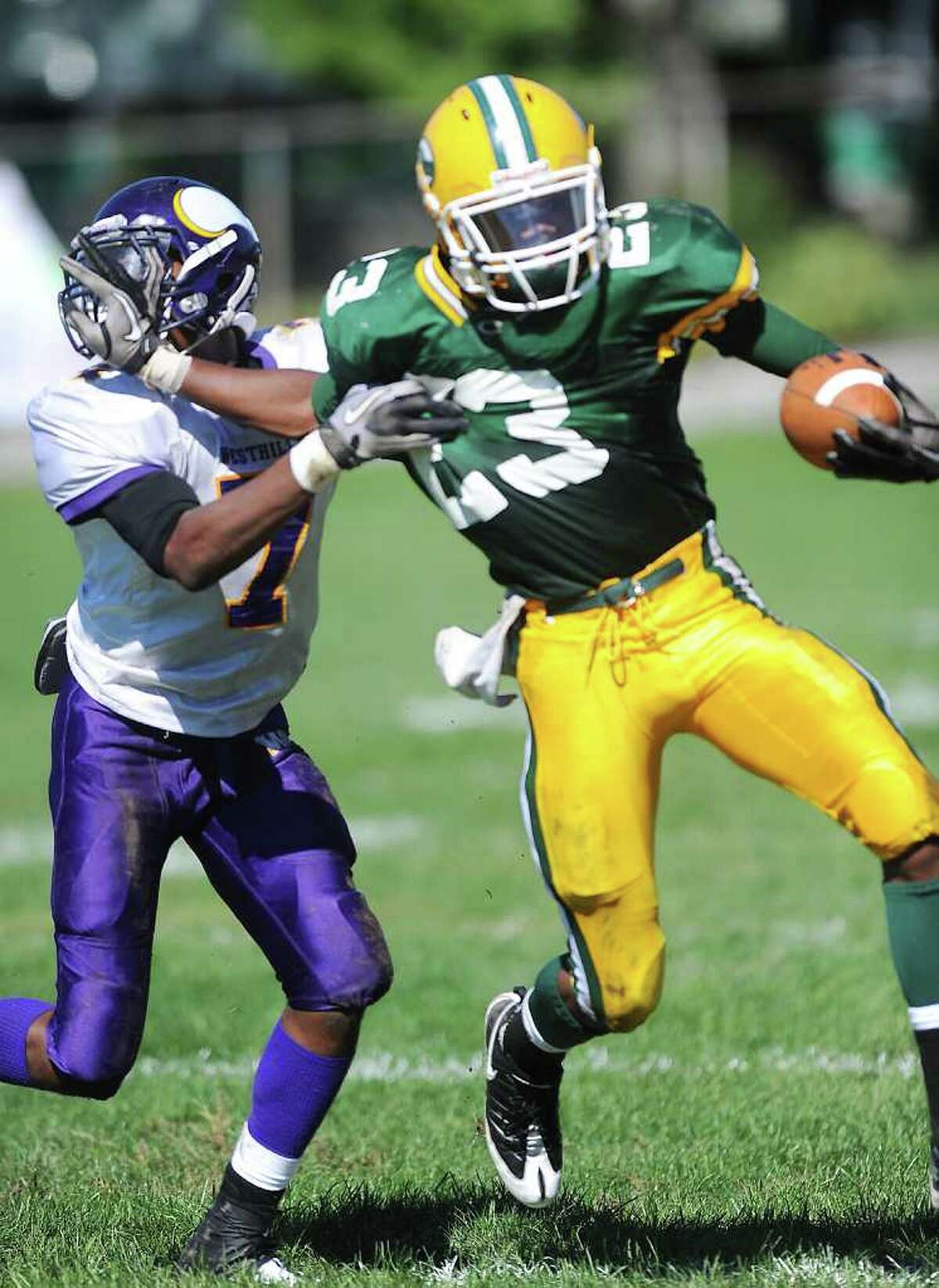 Trinity Catholic High School's Tre Crumbley carries the ball with pressure from Westhill High School's Kieran Bowman in city rivalry football action at Trinity in Stamford, Conn. on Saturday October 2, 2010.