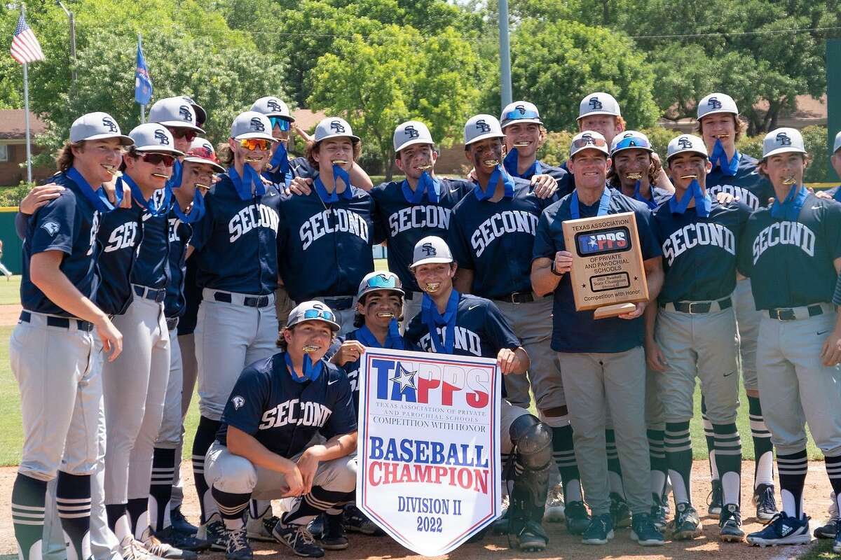 The Second Baptist School baseball players bite their championship medals alongside coach Rayner Noble and display the championship banner and plaque after beating Brook Hill 11-5 in the TAPPS Division II state championship game on the afternoon of May 19 at Clay Cloud Ballpark on the campus of the University of Texas at Arlington.